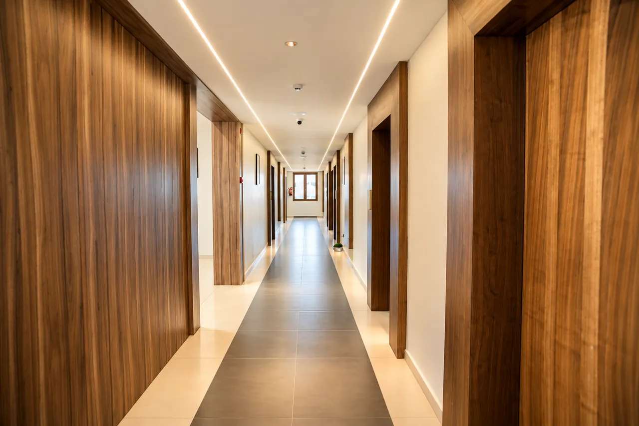 Warmly illuminated guest room corridor with natural wood finishes at Hotel Pumerai