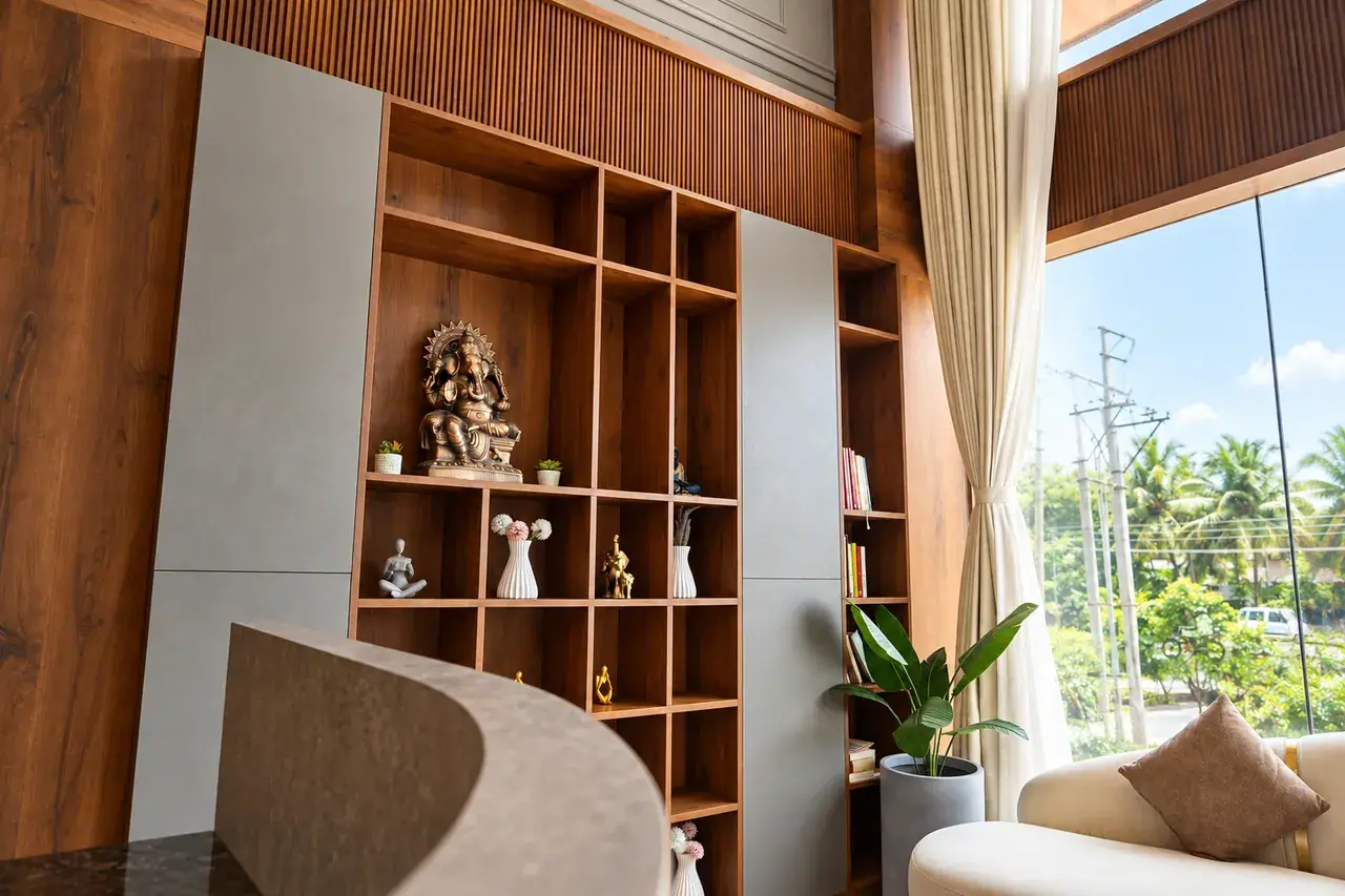 Handcrafted wooden library shelving with brass Ganesha idol and lobby desk at Hotel Pumerai