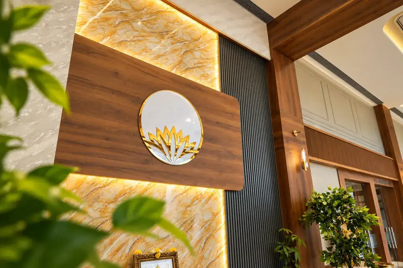 Golden lotus emblem on backlit onyx marble and fluted wood wall at Hotel Pumerai